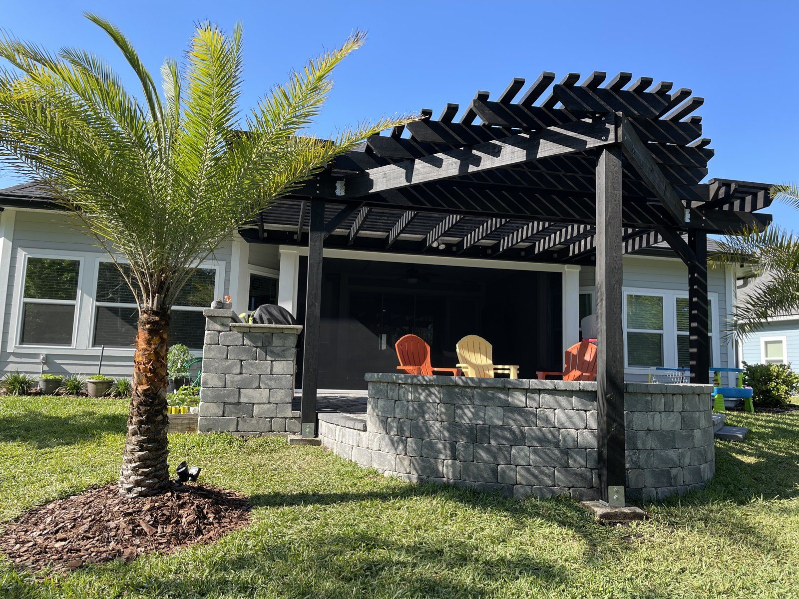 Attached Black Pergola · Paver Seating Wall